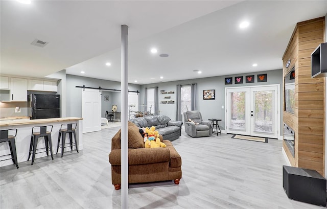 living room featuring a barn door, light hardwood / wood-style floors, and french doors