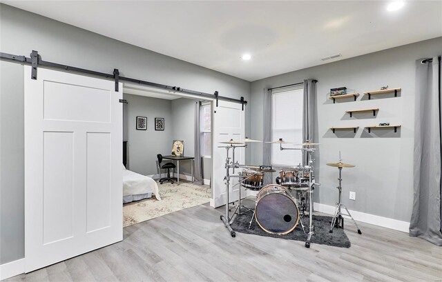 exercise room with a barn door and light wood-type flooring