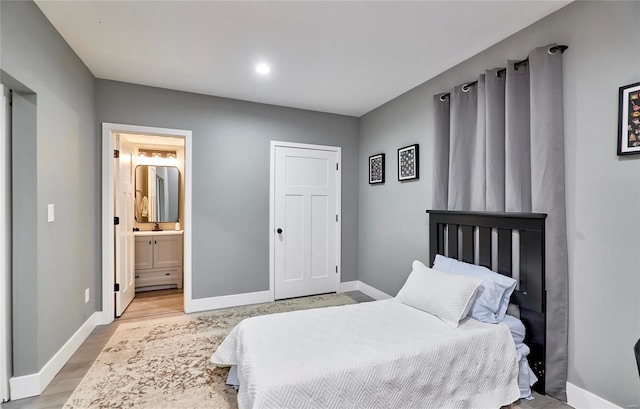 bedroom featuring light hardwood / wood-style floors and ensuite bath