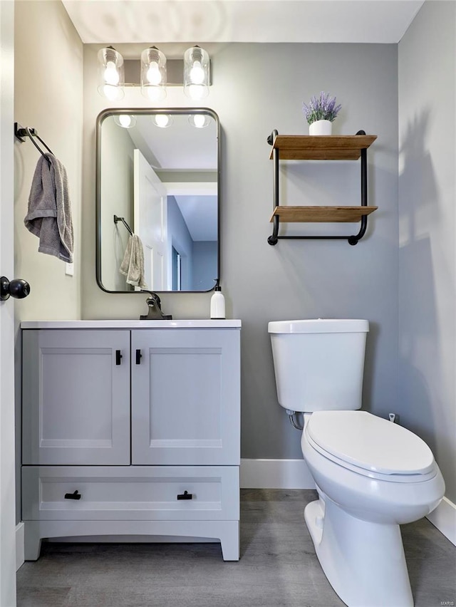 bathroom featuring toilet, vanity, and hardwood / wood-style floors