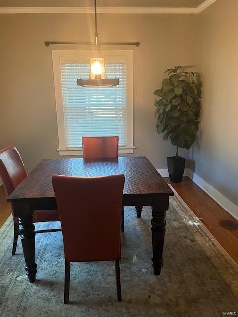 dining space with ornamental molding, hardwood / wood-style floors, and a notable chandelier