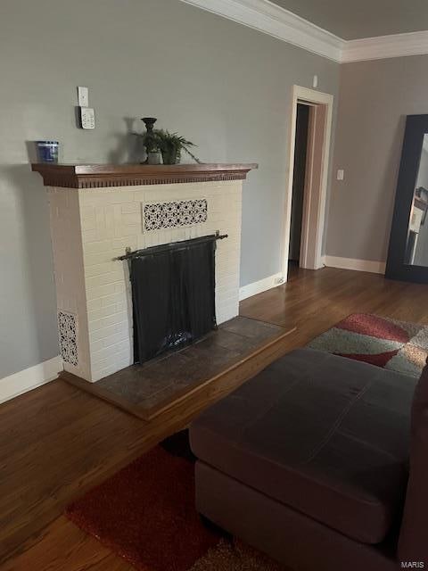 living room featuring dark wood-type flooring, a brick fireplace, and crown molding