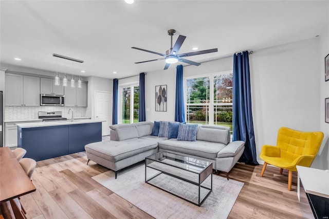 living room with light hardwood / wood-style floors and ceiling fan