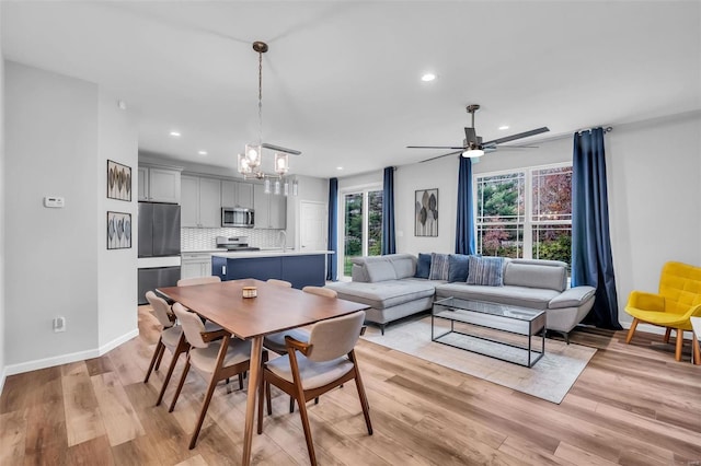 dining space featuring sink, ceiling fan with notable chandelier, and light hardwood / wood-style floors