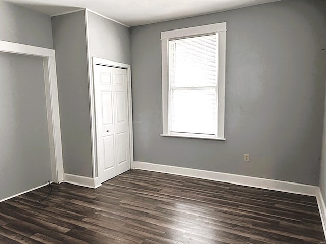 unfurnished bedroom featuring dark hardwood / wood-style flooring and a closet