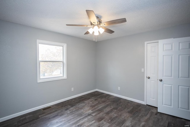 empty room with ceiling fan, a textured ceiling, and dark hardwood / wood-style flooring