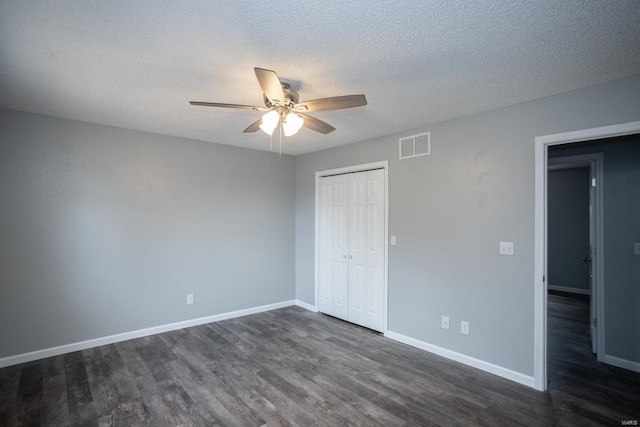 unfurnished bedroom featuring dark hardwood / wood-style flooring, a closet, a textured ceiling, and ceiling fan