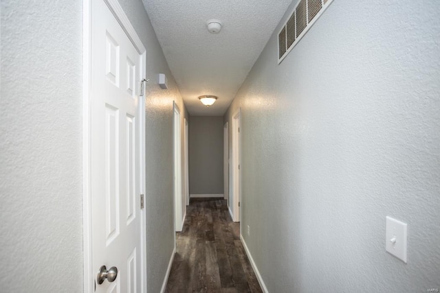 corridor with dark wood-type flooring and a textured ceiling