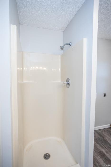 bathroom with hardwood / wood-style floors, a textured ceiling, and walk in shower