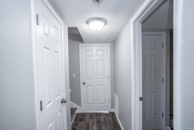 corridor with dark wood-type flooring and a textured ceiling