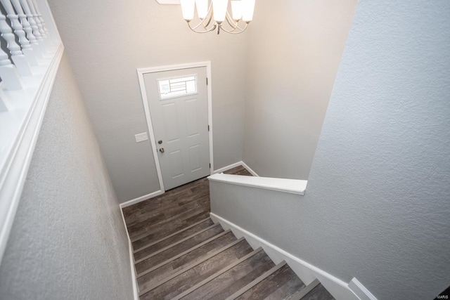 staircase with hardwood / wood-style flooring and a chandelier