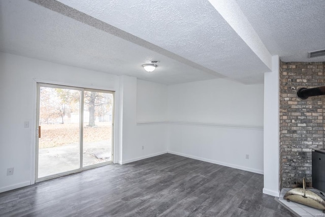 unfurnished living room with a textured ceiling, a wood stove, and dark hardwood / wood-style floors