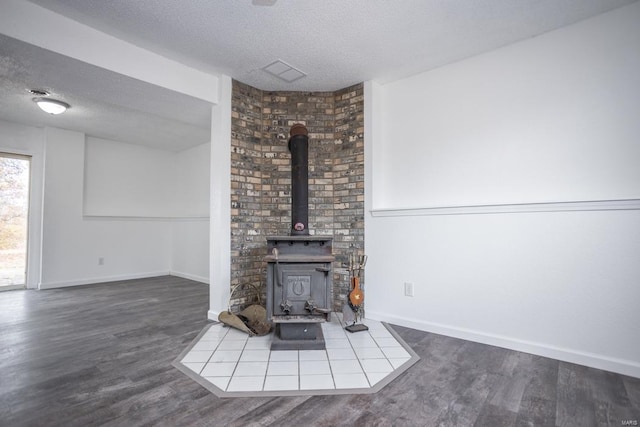 unfurnished living room featuring a wood stove, a textured ceiling, and hardwood / wood-style floors