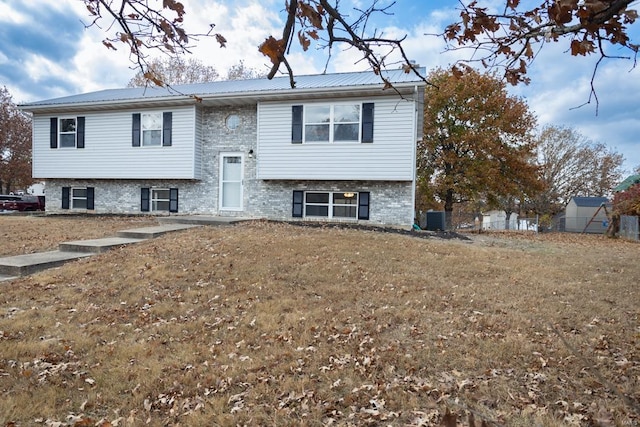 bi-level home featuring a storage unit, a front lawn, and central AC