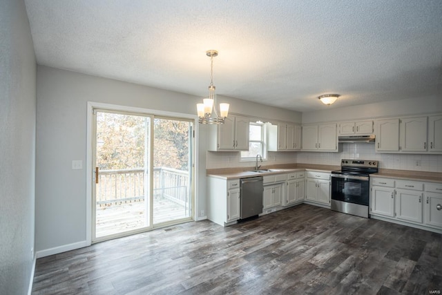 kitchen featuring dark wood-type flooring, white cabinetry, stainless steel appliances, and hanging light fixtures