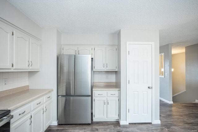 kitchen featuring dark wood-type flooring, tasteful backsplash, appliances with stainless steel finishes, and white cabinets