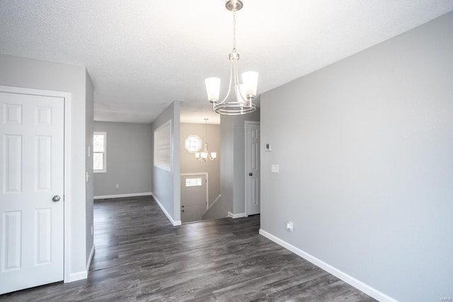 unfurnished dining area featuring an inviting chandelier, dark hardwood / wood-style floors, and a textured ceiling