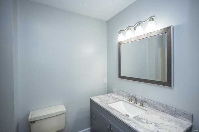 bathroom with toilet, a textured ceiling, and vanity