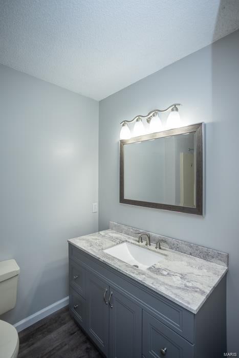 bathroom featuring vanity, a textured ceiling, hardwood / wood-style flooring, and toilet