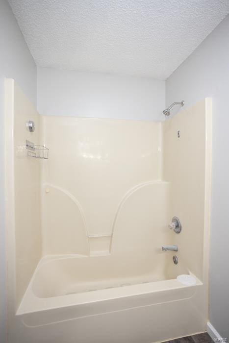 bathroom with a textured ceiling, tub / shower combination, and hardwood / wood-style floors