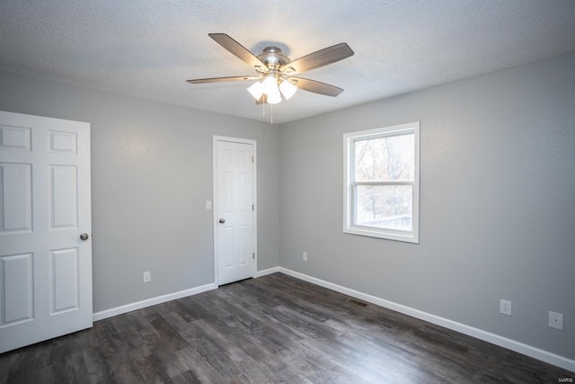 empty room with dark wood-type flooring, a textured ceiling, and ceiling fan