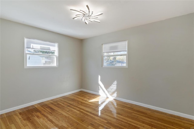 empty room with hardwood / wood-style floors and a notable chandelier