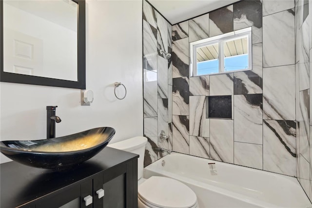 full bathroom featuring vanity, tiled shower / bath, and toilet