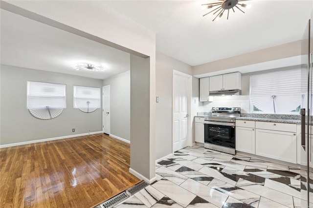 kitchen with backsplash, light stone counters, stainless steel range with electric stovetop, light hardwood / wood-style flooring, and white cabinets