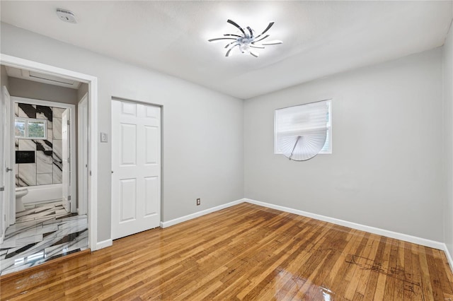 unfurnished bedroom featuring ensuite bathroom and wood-type flooring