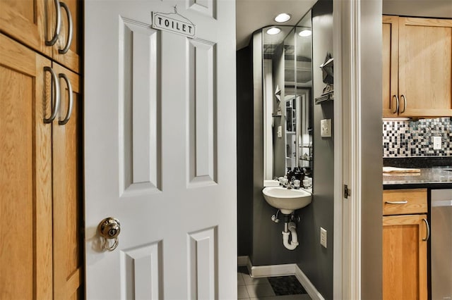 bathroom with tile patterned flooring, sink, and backsplash