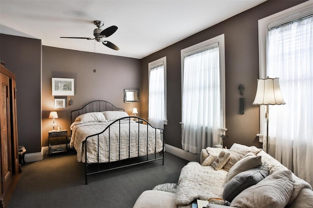 bedroom featuring multiple windows, dark colored carpet, and ceiling fan