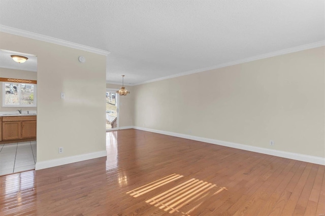 empty room featuring crown molding, plenty of natural light, sink, and hardwood / wood-style floors