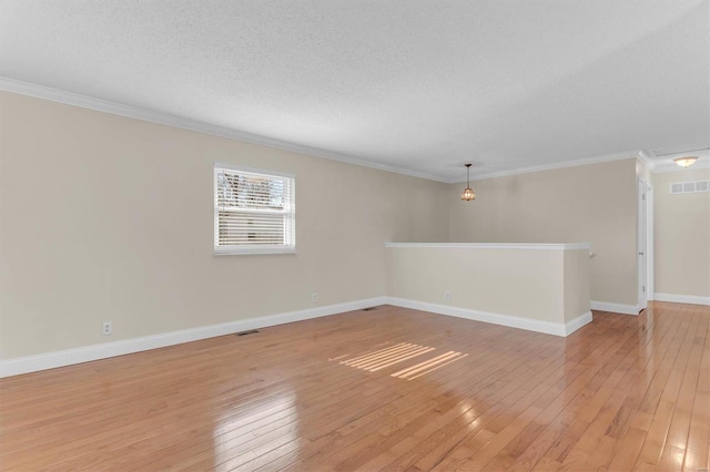 spare room with ornamental molding, a textured ceiling, and light hardwood / wood-style flooring