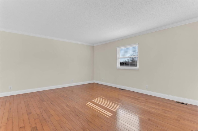 spare room with crown molding, a textured ceiling, and light hardwood / wood-style floors