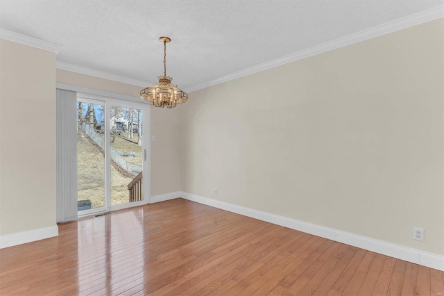 empty room with an inviting chandelier, ornamental molding, light hardwood / wood-style floors, and a textured ceiling