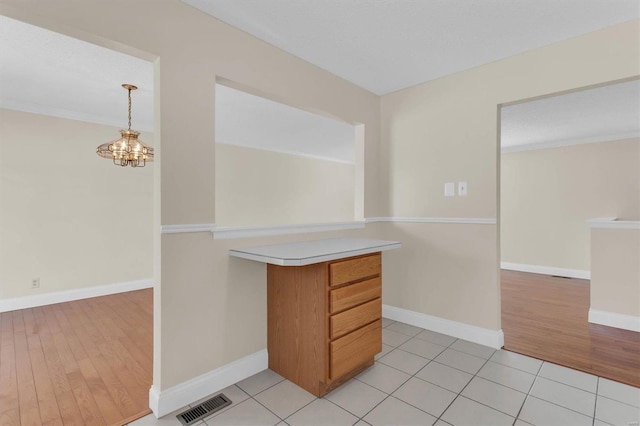 kitchen featuring an inviting chandelier, hanging light fixtures, light tile patterned floors, and ornamental molding