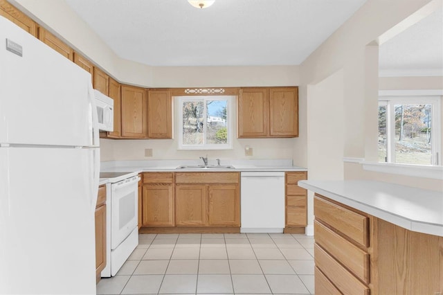 kitchen featuring sink, white appliances, light tile patterned floors, and a healthy amount of sunlight