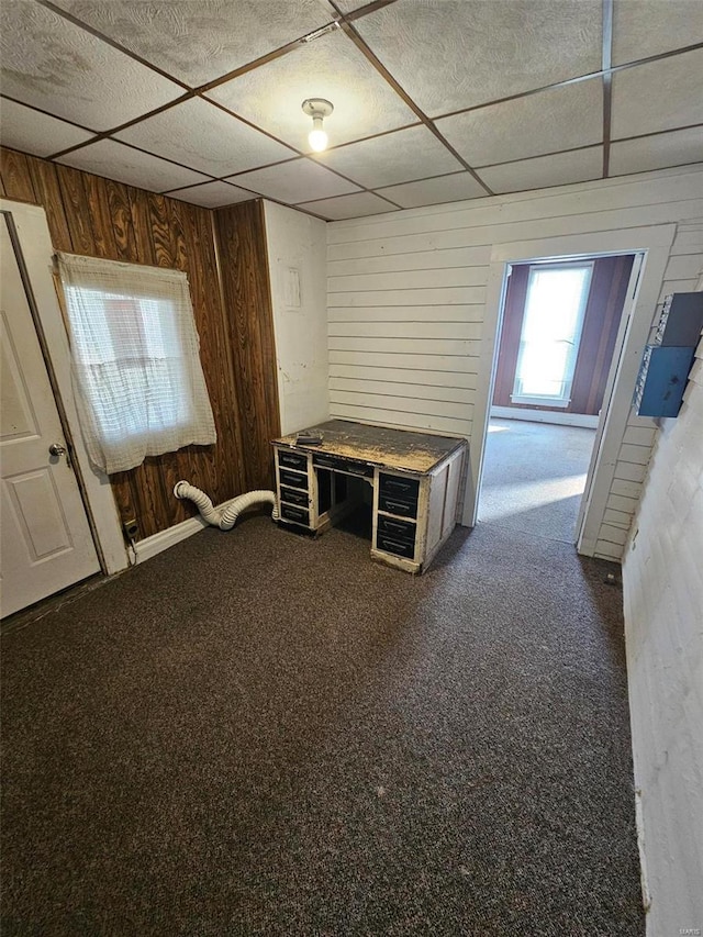 interior space with a paneled ceiling and wood walls