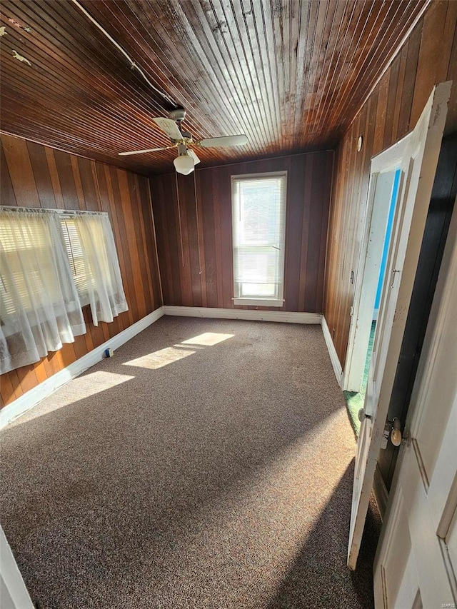 unfurnished room with ceiling fan, carpet floors, and wood ceiling