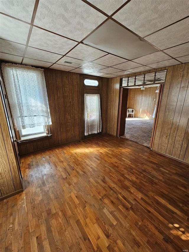 spare room with wooden walls, plenty of natural light, and wood-type flooring