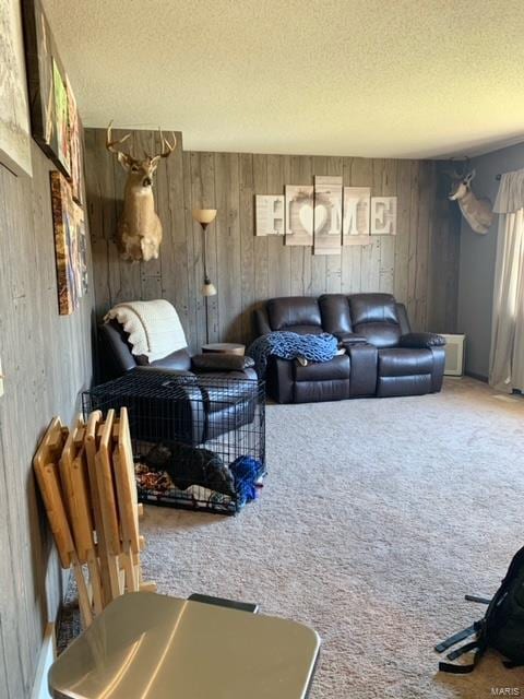 living room featuring carpet floors, wooden walls, and a textured ceiling