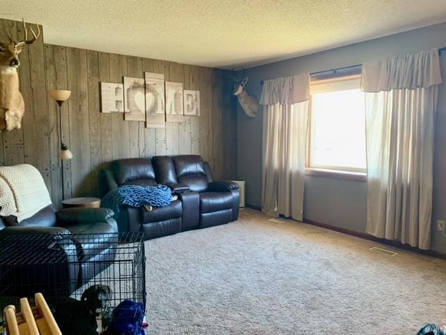 carpeted living room featuring a textured ceiling and wood walls