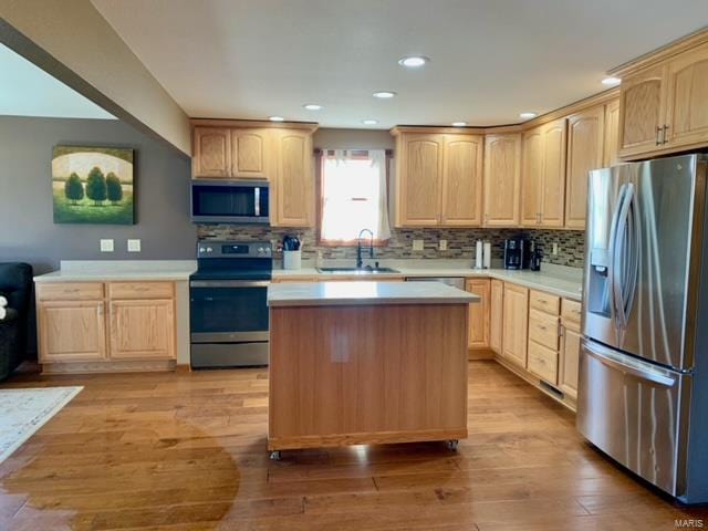 kitchen with appliances with stainless steel finishes, sink, light brown cabinetry, and light hardwood / wood-style flooring