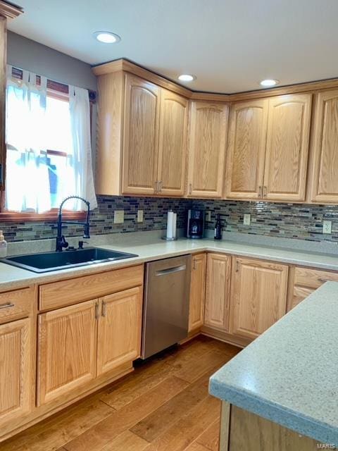 kitchen with light brown cabinetry, tasteful backsplash, dishwasher, sink, and light hardwood / wood-style floors