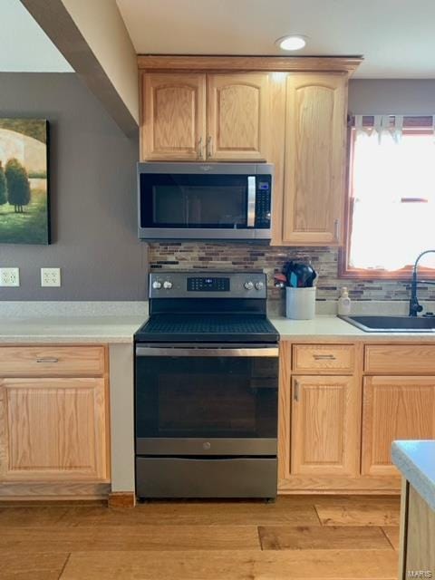 kitchen featuring light brown cabinetry, sink, light wood-type flooring, and appliances with stainless steel finishes