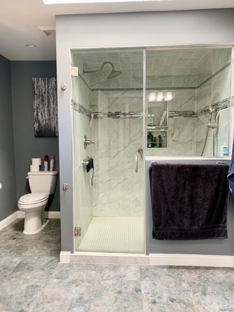 bathroom featuring a shower with shower door and toilet