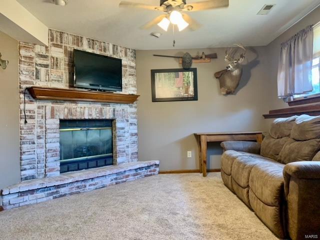 living room featuring ceiling fan, a brick fireplace, and carpet