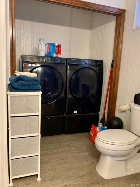 clothes washing area featuring hardwood / wood-style flooring and washing machine and clothes dryer