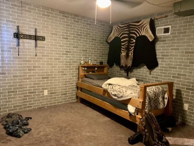 carpeted bedroom featuring brick wall