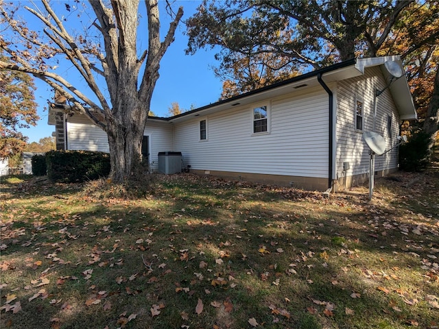 view of side of property with central air condition unit and a yard